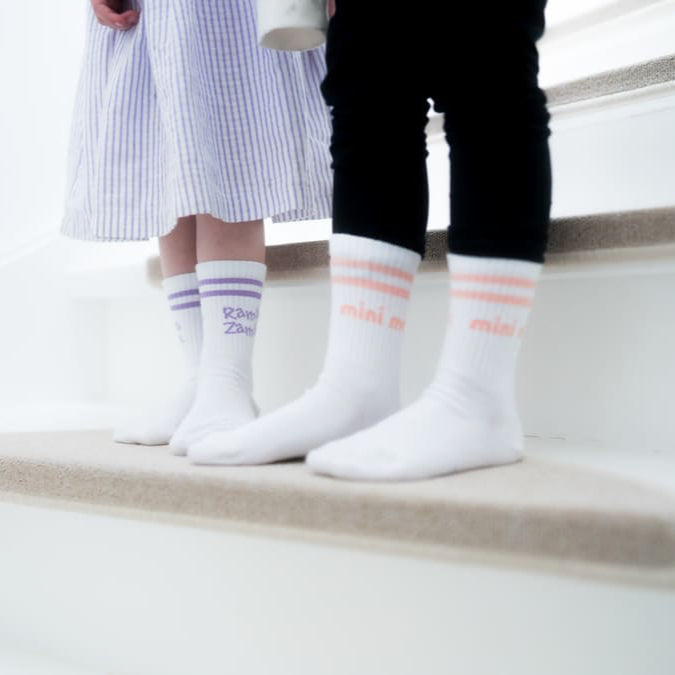 mini me und ramba zamba Socken für Kinder am Kinderfuß auf weißer Treppe