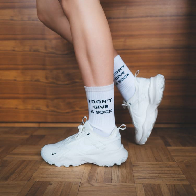 I don't give a sock Statementsocken mit Sneaker vor Holzboden