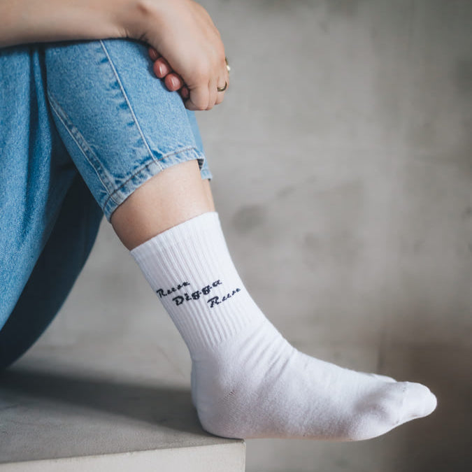 Run Digga Run Statementsocken am Fuß auf Stein vor grauem Hintergrund