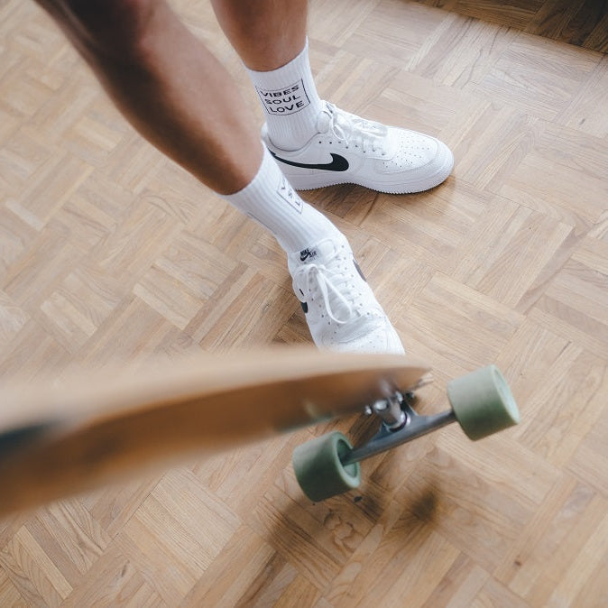 Vibes Soul Love Statementsocken von arrel mit Skateboard auf Holzboden