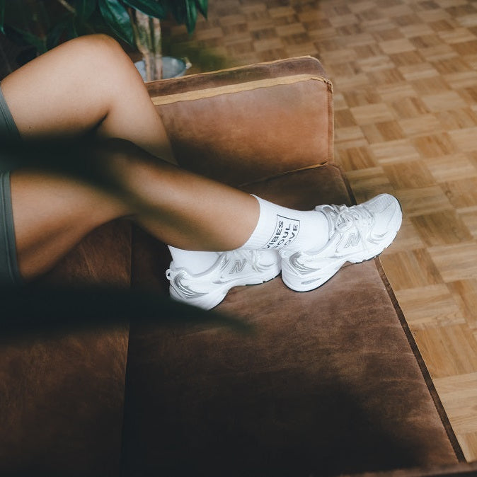 Vibes Soul Love Statementsocken von arrel mit Sneaker an Frau auf Couch