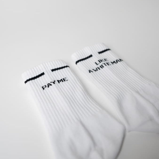 Nahaufnahme der pay me like a white man statement Socken von arrel in weiß mit schwarzem Design