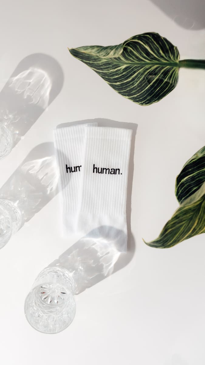 human. Statementsocken von arrel in weiß aus Bio-Baumwolle mit Glas und Pflanze
