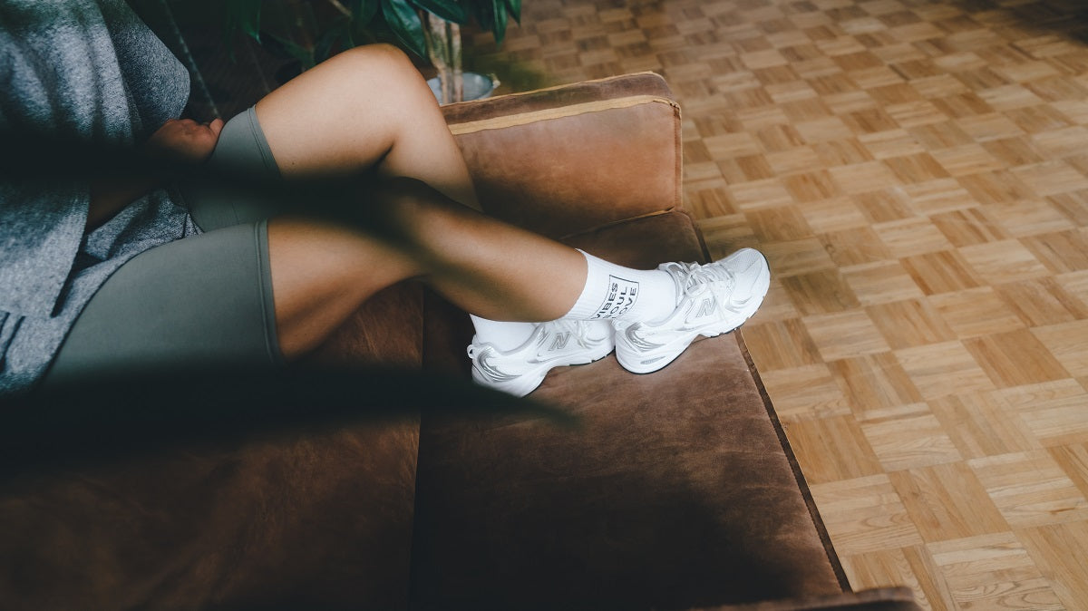 Vibes Soul Love Statementsocken von arrel mit Sneaker an Frau auf Couch
