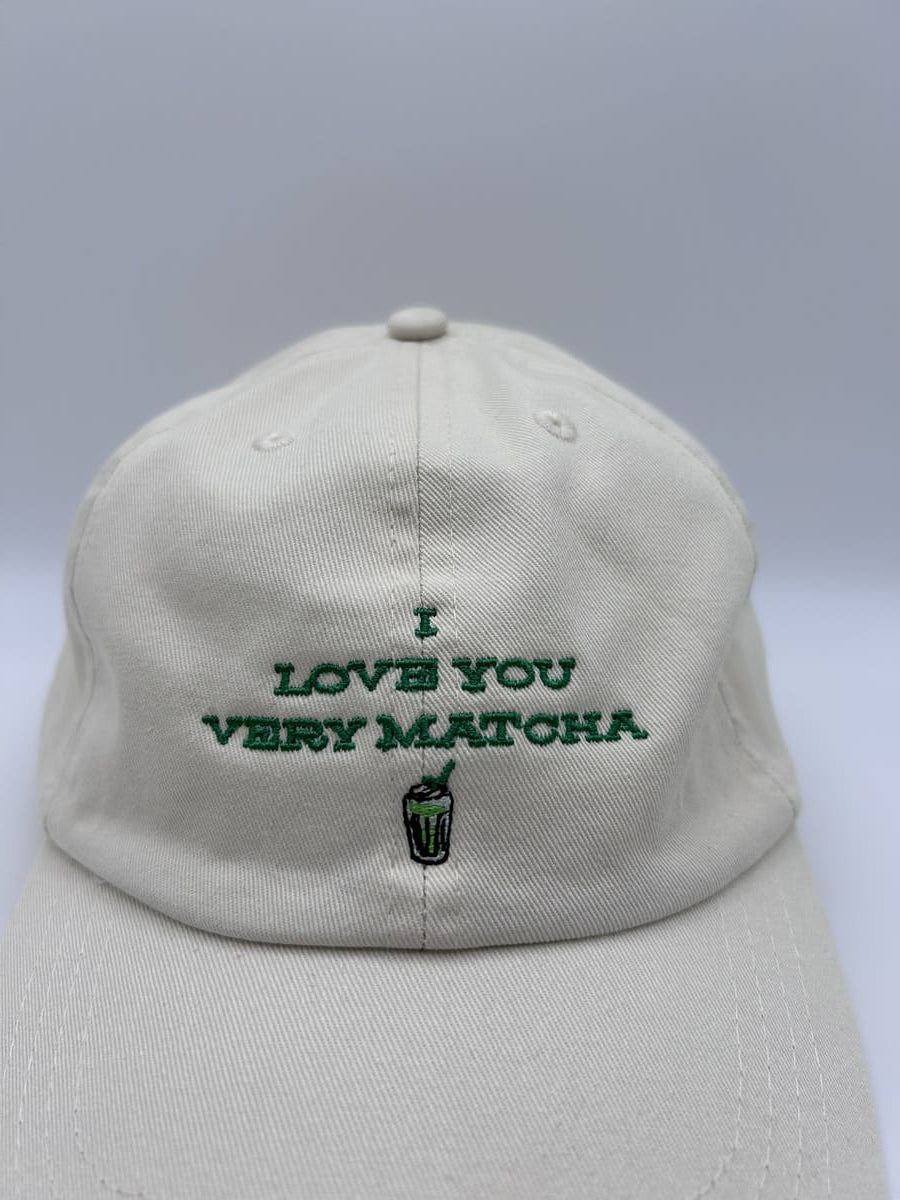 Nahaufnahme der I love you very matcha dad cap von arrel in beige mit grüner Schrift